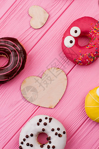 甜圈和彩色背景上的木心各种甜圈和胶合板心平铺在粉红色图片