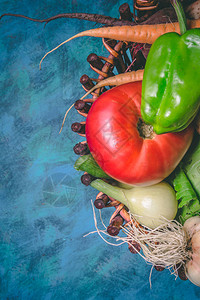 番茄卷心菜洋葱土豆胡椒大蒜胡萝卜和甜菜根蓝色背景上篮子里的蔬菜复制空图片