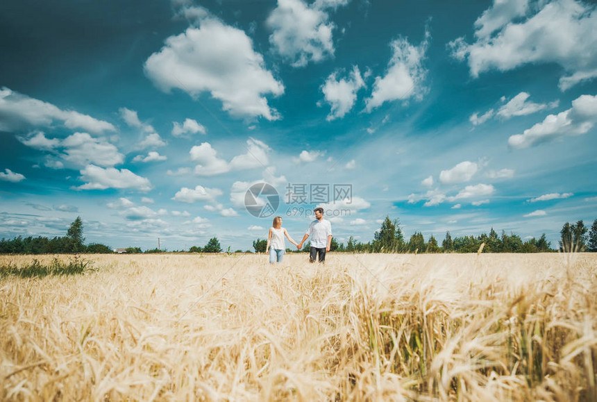 年轻夫妇在远处穿过田野时手图片