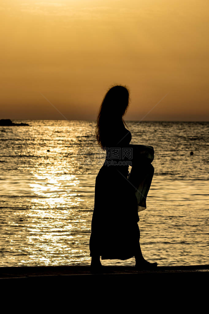 美丽的女剪影无法辨认的苗条高个女人与丝巾在的爱奥尼亚海水前夕阳从阿尔巴尼亚卡萨米尔看到的五颜六色图片
