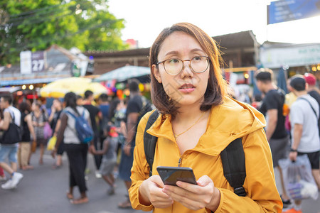 肖像美丽的亚洲女站在泰国乍都市场拿着智能手机曼谷是外国图片