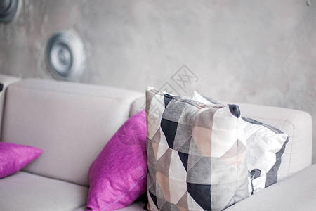 灰色沙发和紫色枕头的照片在灰色墙壁的房间里图片