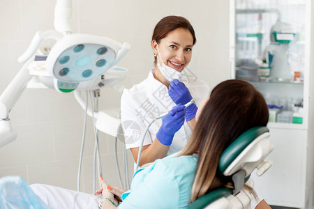 女牙医治疗病人一名戴着面具的妇女坐在诊所的牙科椅上医学健图片