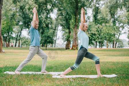 成年男女在公园练瑜伽时站在瑜伽垫子图片