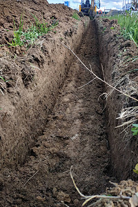 为电线或电缆挖掘浅沟槽的建筑挖土机图片