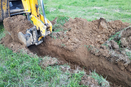 为电线或电缆挖掘浅沟槽的建筑挖土机图片
