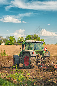 在农场工作的拖拉机现代农业运输在田间工作的农民肥沃的土地阳光背景下的拖拉机耕图片