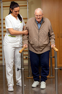 全长肖像的年轻女护士协助老年患者治疗棒老人在双图片