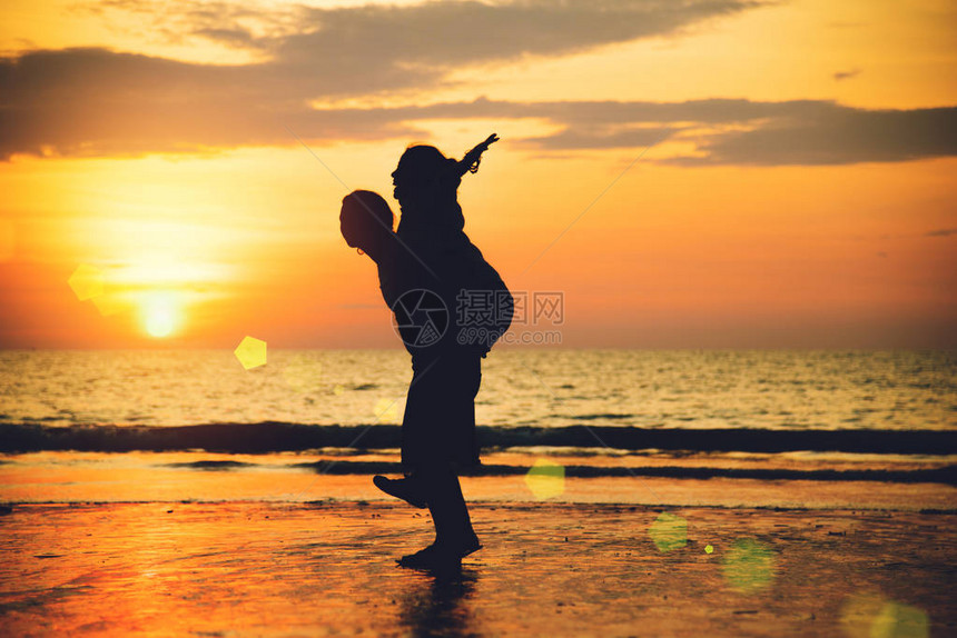 亚裔情侣在海滩上快乐的情侣在背景男人举起女人图片