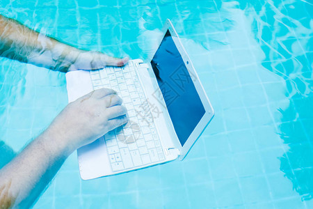 使用笔记本电脑在水下工作的男手妨碍工作的概念模图片