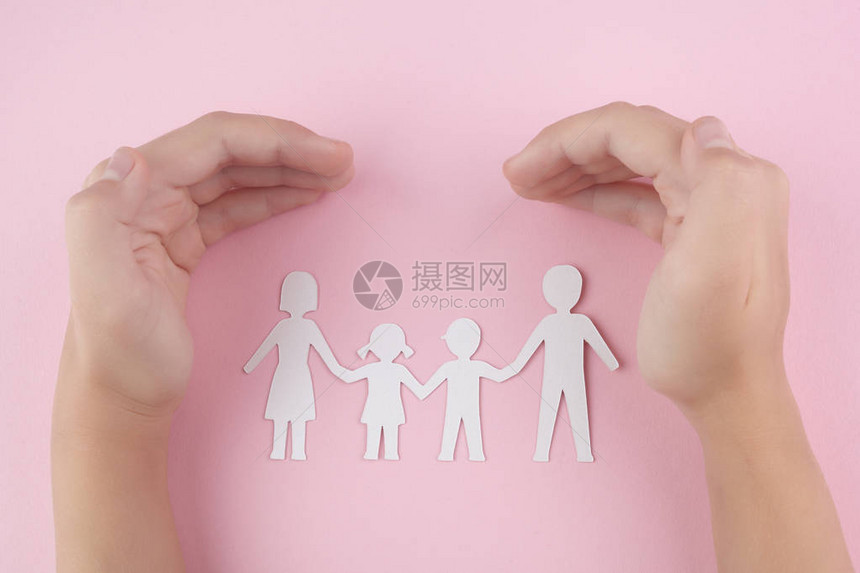 保护儿童手在粉红背景上保护家庭白纸剪图片