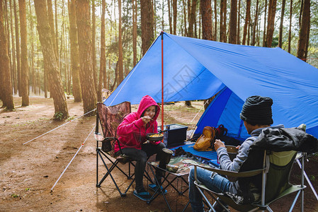 享受野营在松树林中度过快乐的亚裔年轻夫妇图片