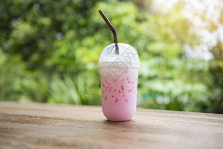 夏季在塑料杯果汁中喝粉红色草莓奶粉红花状冰饮料图片