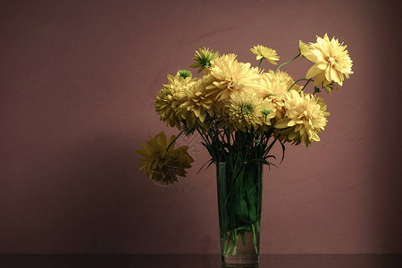 黑色玻璃桌上的花瓶里的黄色花朵美丽图片