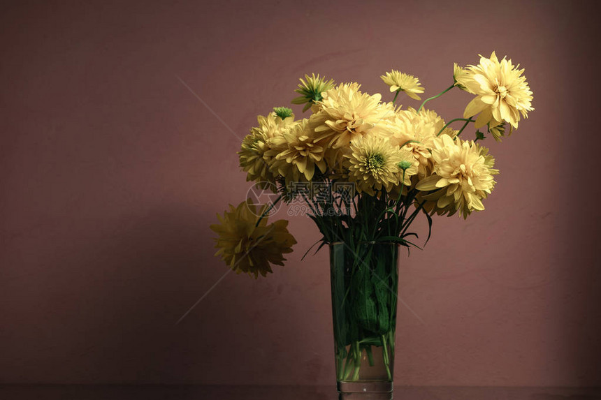 黑色玻璃桌上的花瓶里的黄色花朵美丽图片