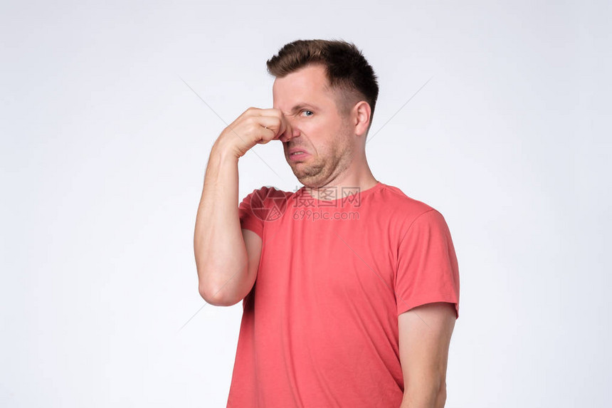 穿着红色T恤插头鼻子的不高兴的年轻人闻起来有股臭味和不愉快的气味图片