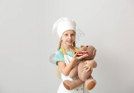 可爱的小厨师喂小玩具熊用图片