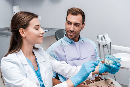 男人有选择焦点看着快乐的牙医在牙齿模型图片