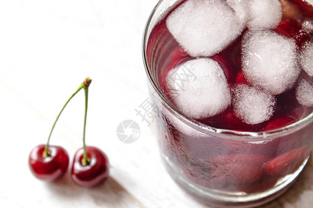 新鲜的樱桃鸡尾酒加冰在白色木制背景上新鲜的夏季鸡尾酒配樱桃图片