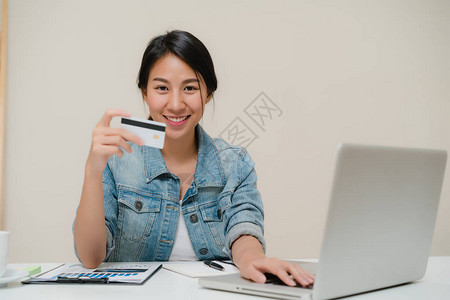 美丽的亚洲智能商务女使用电脑或笔记本电脑通过信用卡购买网上购物图片