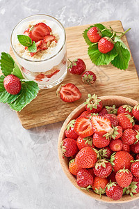 草莓颗粒或玻璃中的冰沙和木碗中新鲜的浆图片