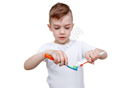 t恤的五岁小男孩在刷子上挤牙膏背景图片