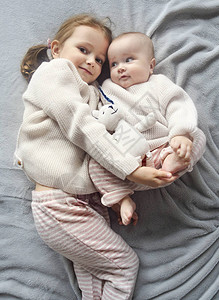 可爱的高加索女孩姐妹在床上抱着小婴儿的生活方式肖像图片