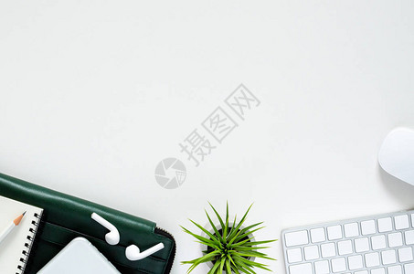 现代工作场所配备无线和鼠标配备无线耳机的智能手机铅笔记本绿色文件袋和白色背景上的铁兰空气植物顶视背景图片