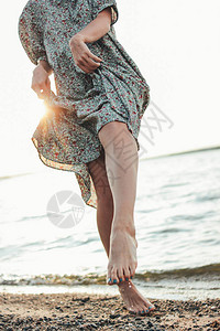 在沙滩上穿着衣服的年轻浪漫女人的腿部夏假时图片