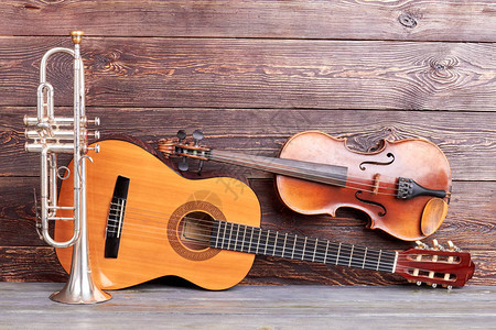 复古风格的乐器木制背景上的小号原声吉他和小提图片
