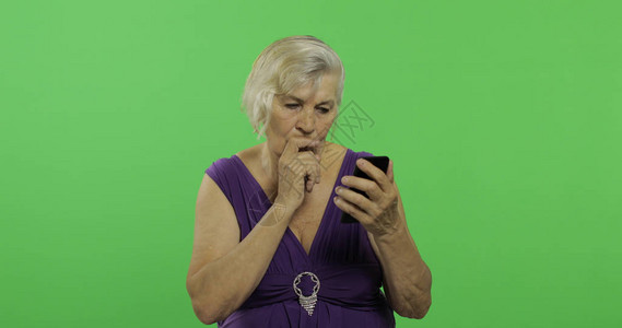 年长妇女用智能手机工作图片