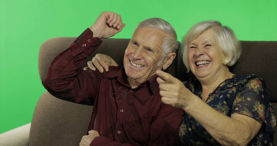 老年男女一起坐在沙发上看电视笑色度键背景老年幸福家庭的概图片