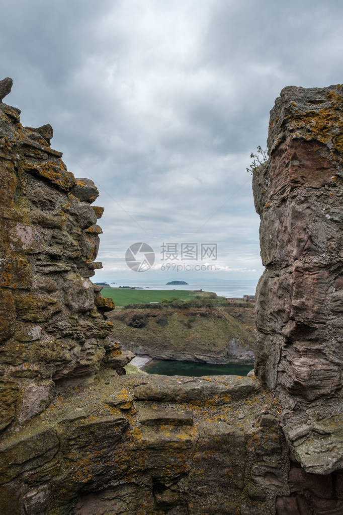 从苏格兰东洛西安14世纪塔尔隆城堡废墟的坡道上观望一个小海湾和悬崖向克雷图片