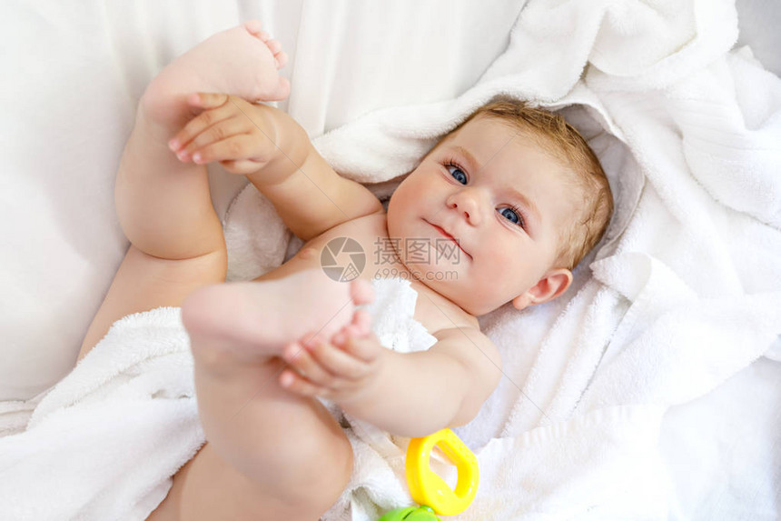 可爱的小宝洗澡后玩具拨浪鼓和自己的脚可爱的漂亮女孩裹着白毛巾快图片