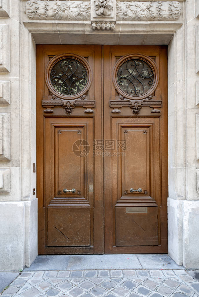 法国巴黎历史建筑双门入口带有雕塑细节的灰泥墙的复古木制门口和石雕花装饰带有圆形格栅的华丽雕刻木门古色图片
