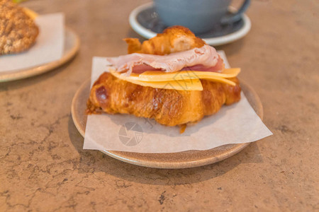 石桌上的咖啡和羊角面包三明治法式早餐奶酪火腿烤羊角面包和拿铁咖啡简单图片
