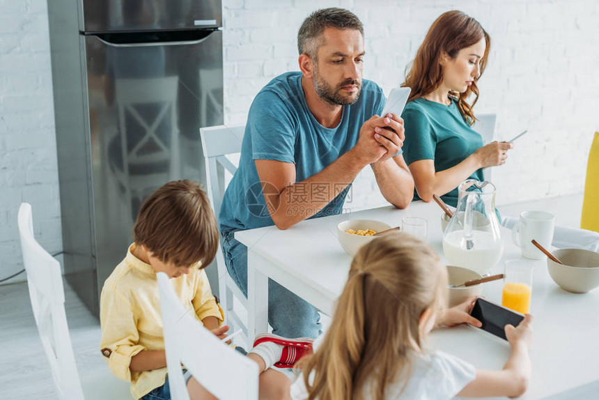 带着女儿和som的父母坐在餐桌旁的厨房里用智能图片