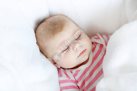 可爱的新生婴儿躺在毯子上的白色床上图片