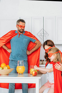 家庭穿着超级英雄的装扮吃早餐而父亲用图片