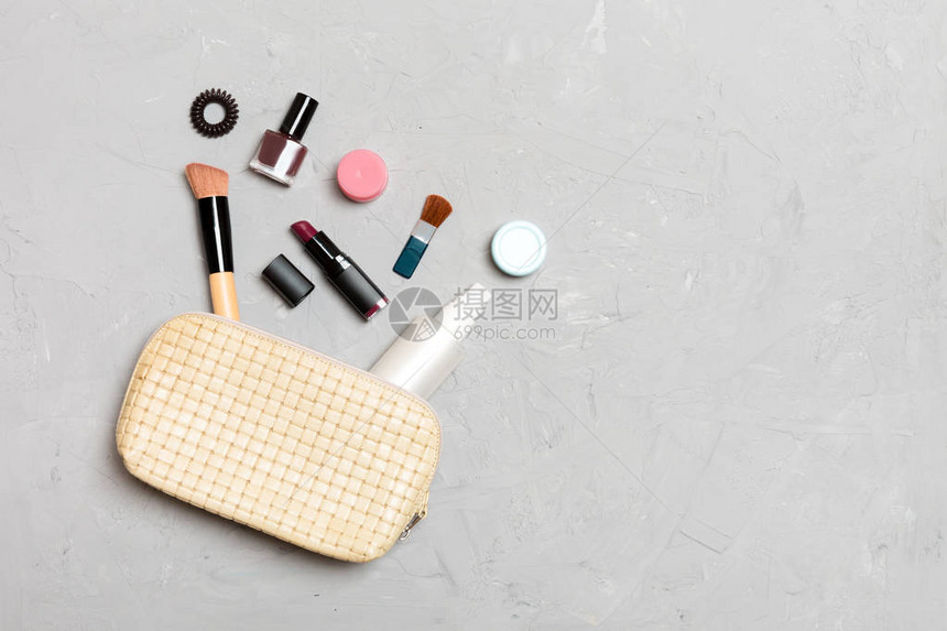 化妆品袋的顶端产品在水泥背景上从化妆品袋中掉落出来图片