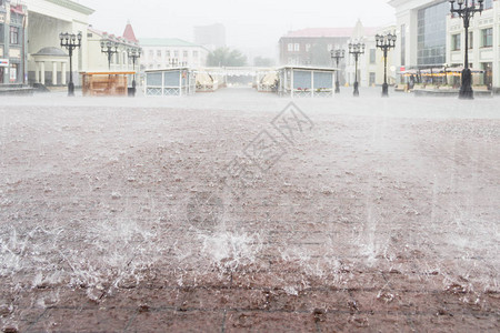 大雨在城市在大雨滴的水下用棕色矩形瓷砖关闭人行道市中心的广场图片