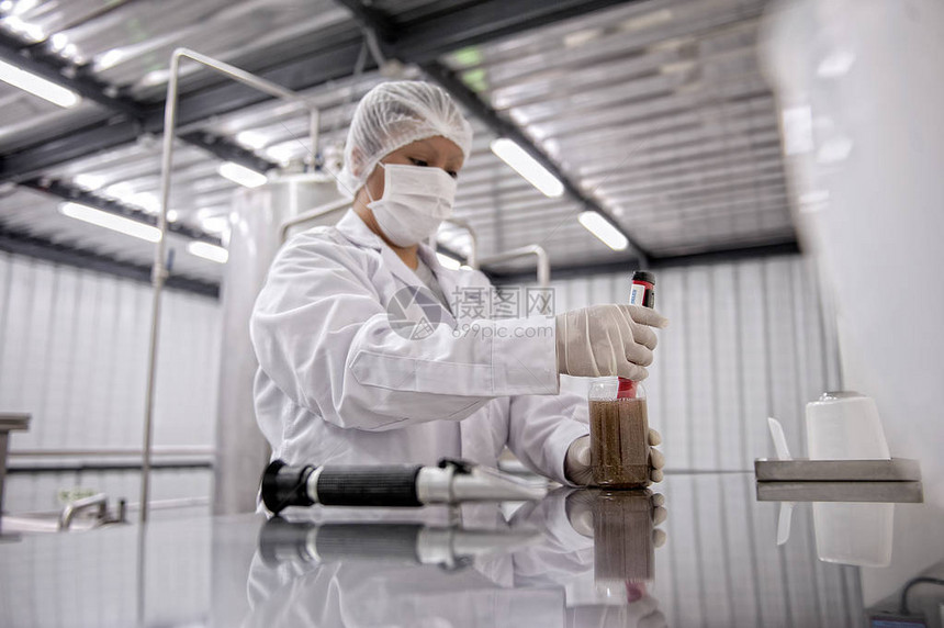 受保护的女科学家在实验室内用面具和手套分析液剂图片