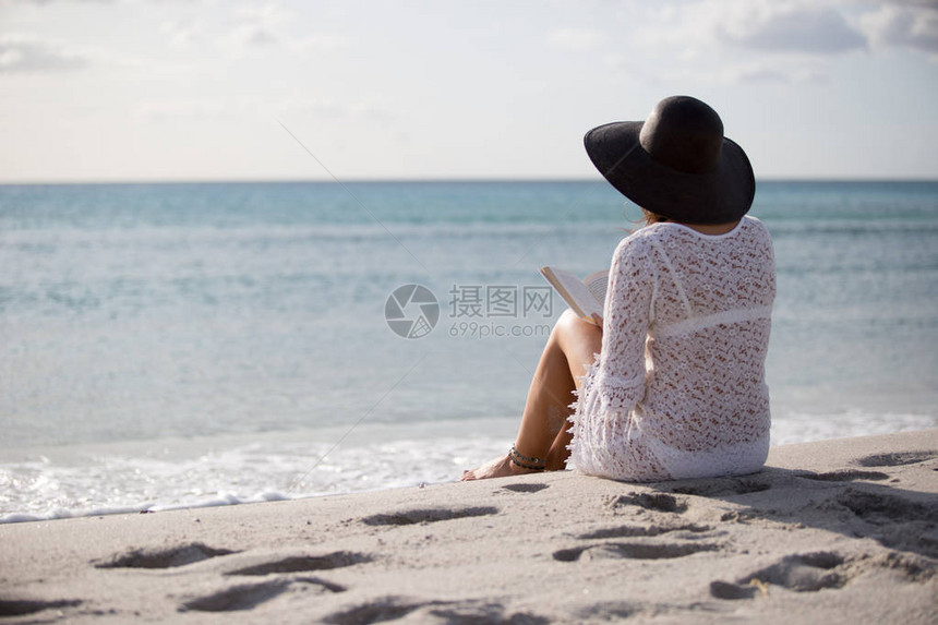 一位身后躺在海边的年轻女子在风中黎明时仰望地平线图片