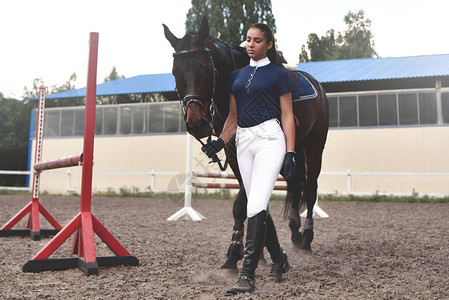 年轻女子领着她的马去训练为比赛做准备图片