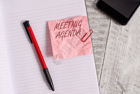 写上去显示会议程的概念手写概念意义议程对会议所需的内容设定了明确的期望皱纹纸笔记本和放置在木质背景