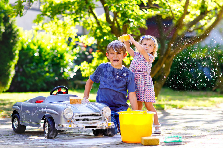 两个快乐的孩子在夏日花园里洗大旧玩具车图片