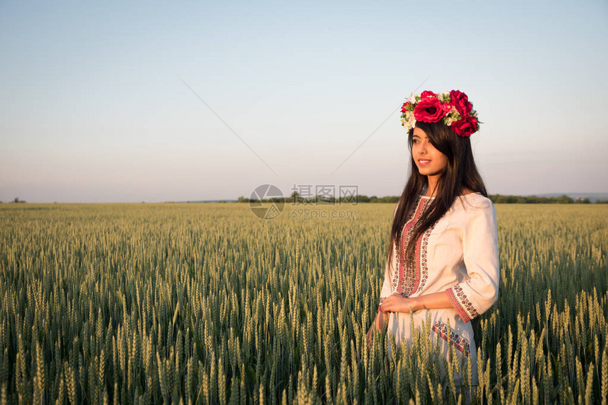 穿着乌克兰刺绣的印度女人在田野里摆姿势美丽的印度年轻女子穿着传统的乌克兰刺绣衣服和手工制作的花环站在田野里图片