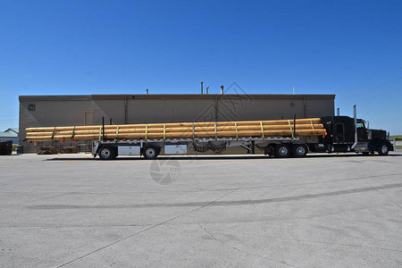 一辆半拖车正在搬运额外的长的木杆背景图片