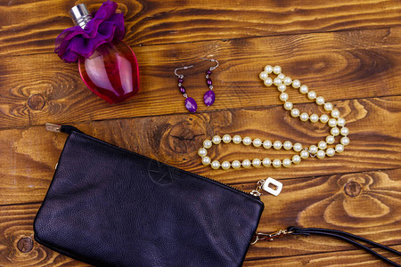 木制背景上的女配饰木桌上的手拿包香水瓶珍珠项链和耳环美容和时尚组成图片