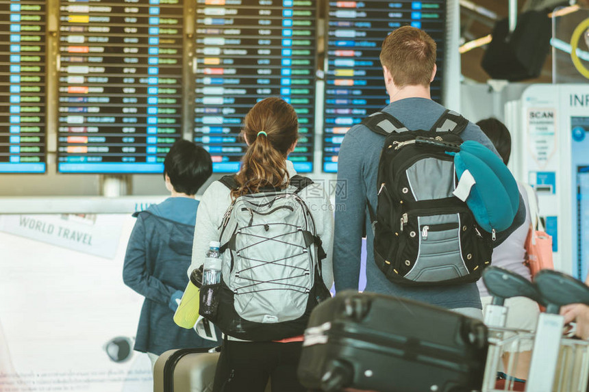 乘客在国际机场查看航班信息板并检查他们的航班图片
